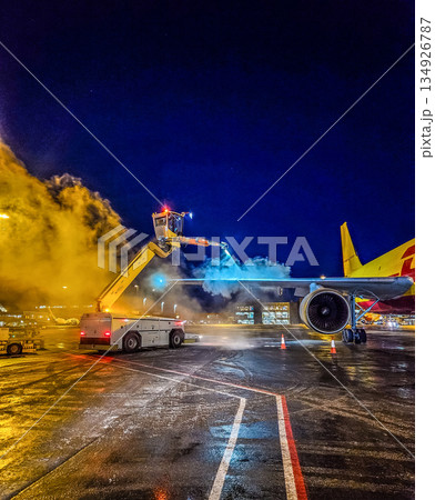 Aircraft Deicing Operation at Night Airport Cargo Plane Winter Maintenance with Steam and Blue Spray Equipment Ground Service 134926787