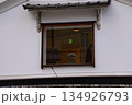 Close-up of the window of a building from the view of street in Kyoto Japan. A decoration in the window with the exit sign in the background. 134926793