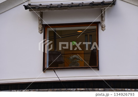 Close-up of the window of a building from the view of street in Kyoto Japan. A decoration in the window with the exit sign in the background. 134926793