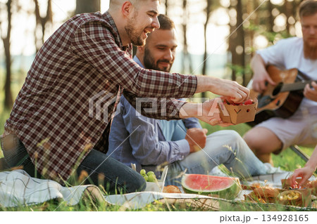 Summertime bonding. Group of friends are having picnic on the field with food in eco boxes 134928165