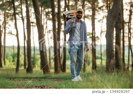 Walking forward. Handsome man is in the forest with acoustic guitar Walking forward. Handsome man is in the forest with acoustic guitar 134928197
