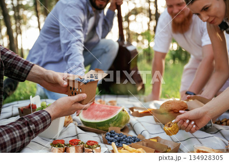 Conception of free time, wellness. Group of friends are having picnic on the field with food in eco boxes Conception of free time, wellness. Group of friends are having picnic on the field with food in eco boxes 134928305