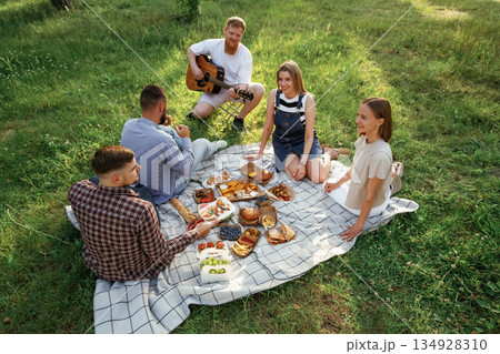 Positive mood, having fun. Group of friends are having picnic on the field with food in eco boxes 134928310