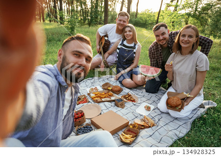 Making the selfie, sitting. Group of friends are having picnic on the field with food in eco boxes 134928325