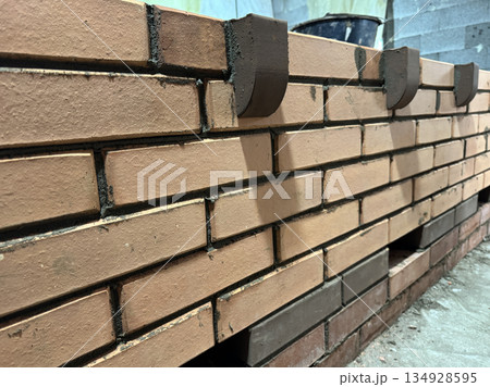 Fresh brickwork of a heating stove bench with decorative elements. Close-up. 134928595