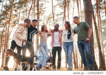 Full height photo, standing with dog. Group of friends are together in the forest Full height photo, standing with dog. Group of friends are together in the forest 134928647