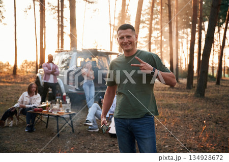 Happy man is smiling. Group of friends are together in the forest Happy man is smiling. Group of friends are together in the forest 134928672
