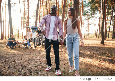 Couple are holding each other by the hands, walking. Group of friends are together in the forest 134928802