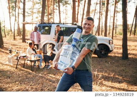 Man with fresh water. Group of friends are together in the forest Man with fresh water. Group of friends are together in the forest 134928819