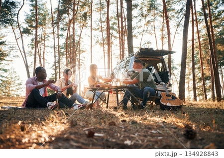 Against the car. Group of friends are together in the forest Against the car. Group of friends are together in the forest 134928843