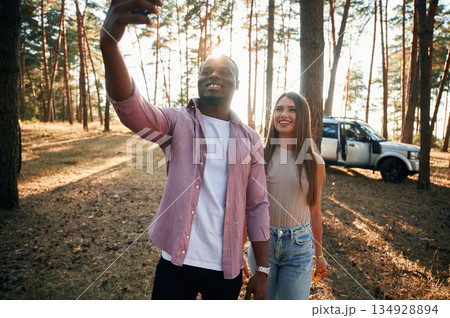 Taking selfie. Black man and white woman as couple are in the forest Taking selfie. Black man and white woman as couple are in the forest 134928894