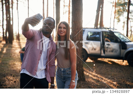 Taking selfie. Black man and white woman as couple are in the forest Taking selfie. Black man and white woman as couple are in the forest 134928897