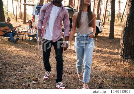 Couple are holding each other by the hands, walking. Group of friends are together in the forest Couple are holding each other by the hands, walking. Group of friends are together in the forest 134928902