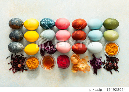 Brightly colored Easter eggs , showcasing various hues created from natural dye sources. Fresh ingredients are displayed alongside such as beets, turmeric and hibiscus, red cabbage and onion peel 134928934