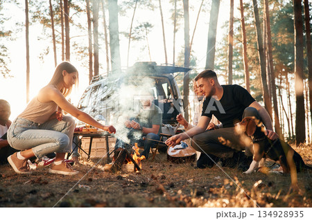 By bonfire. Group of friends are together in the forest By bonfire. Group of friends are together in the forest 134928935