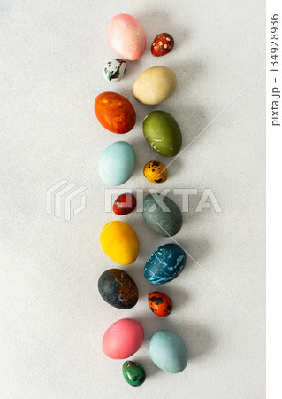 Various Easter eggs in vibrant colors and patterns are neatly arranged, showcasing the joy and creativity associated with spring celebrations and family gatherings 134928936