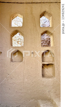 Sunsoaked Brickwork With Niches, Weathered Plaster Showcases Historic Architectural Charm, Sunlit Mudbrick Surface With Arched Recesses Highlighting Aged Craftsmanship And Tranquil Design Elements 134929241