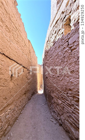 Traveler Meanders Sunny Slender Street, Bright Corridor Bordered By Tall Adobe Buildings, Alley Bathed In Sunlight Where Explorer Navigates Through Narrow Passageway Surrounded By Towering Adobe Walls Traveler Meanders Sunny Slender Street, Bright Corridor Bordered By Tall Adobe Buildings, Alley Bathed In Sunlight Where Explorer Navigates Through Narrow Passageway Surrounded By Towering Adobe Walls 134929250