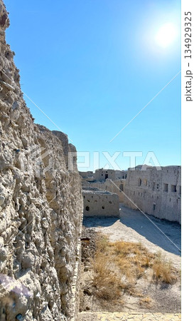 Vivid Desert Scene Highlights Sunlit Fortress With Stark Shadows And Dry Terrain, Dramatic Desert Landscape Showcases Fortress Bathed In Bright Sunlight With Contrasting Shadows And Arid Ground 134929325