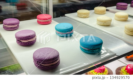 Assorted colorful french macarons in purple, blue, and white colors on a tray in a bakery display 134929570