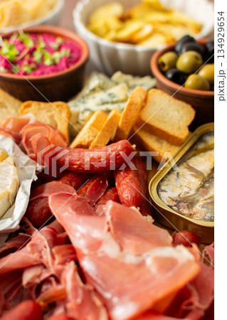 A colorful charcuterie board offers an inviting selection of cheeses, cured meats, fresh bread, nuts, and creamy hummus, perfect for sharing at a casual gathering or picnic A colorful charcuterie board offers an inviting selection of cheeses, cured meats, fresh bread, nuts, and creamy hummus, perfect for sharing at a casual gathering or picnic 134929654