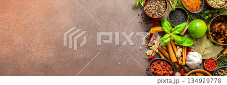 A visually striking arrangement of fresh spices and herbs on a brown surface, highlighting their vivid colors, intricate details, and rich culinary essence, banner 134929778