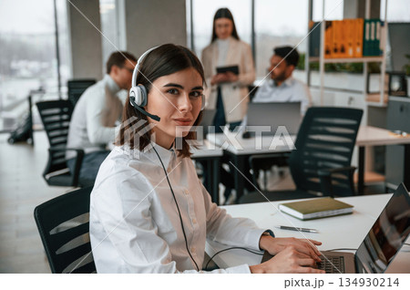 Woman is working by laptop. Four people are working in the office together Woman is working by laptop. Four people are working in the office together 134930214