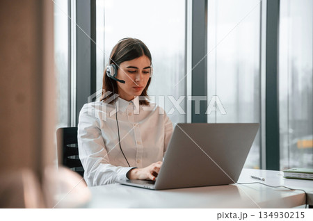 Beautiful young woman is working in the office by laptop Beautiful young woman is working in the office by laptop 134930215
