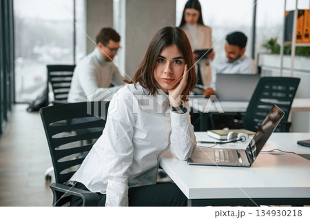 Gorgeous woman is in the front of her colleagues. Four people are working in the office together Gorgeous woman is in the front of her colleagues. Four people are working in the office together 134930218