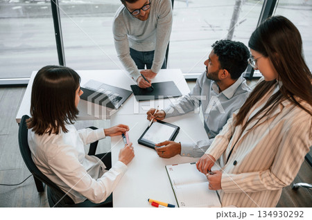 Using tablet. Four people are working in the office together Using tablet. Four people are working in the office together 134930292