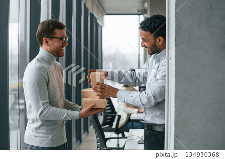 Men are holding eco paper boxes in hands. Business people are working together in the office Men are holding eco paper boxes in hands. Business people are working together in the office 134930368