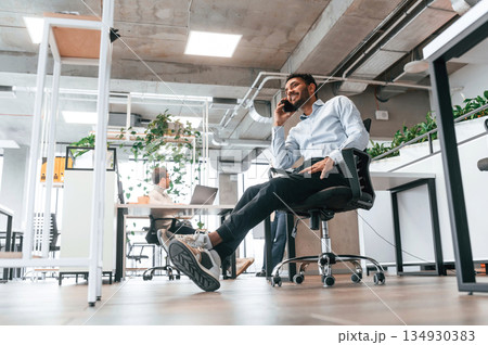 Handsome indian man is sitting on the chair and working in the office Handsome indian man is sitting on the chair and working in the office 134930383
