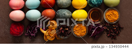 A vibrant assortment of Easter eggs rests on a surface, beautifully dyed in various colors. Natural dye ingredients, such as beets, turmeric and hibiscus, red cabbage and onion peel, vinegar, banner A vibrant assortment of Easter eggs rests on a surface, beautifully dyed in various colors. Natural dye ingredients, such as beets, turmeric and hibiscus, red cabbage and onion peel, vinegar, banner 134930444
