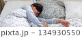 A 50-year-old woman is peacefully sleeping in a cozy bed. She wears a sleep mask and is snuggled under soft blankets, creating a serene atmosphere for rest, banner 134930550