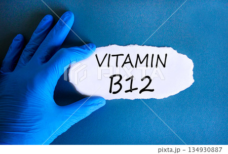 Vitamin B12 symbol. Concept words Vitamin B12 on beautiful white paper. Doctor's hand in blue medical glove. Beautiful blue background. Medical healthy lifestyle Vitamin B12 concept. 134930887