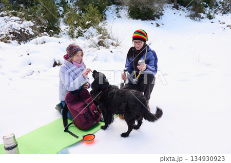 Friends Enjoy A Snowy Winter Picnic With Dog On Snowy Trail Friends Enjoy A Snowy Winter Picnic With Dog On Snowy Trail 134930923