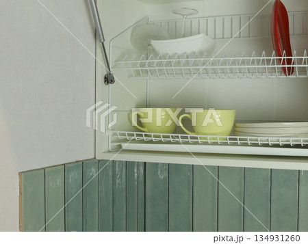 Plates and cups drying on a rack inside a kitchen cabinet after washing dishes Plates and cups drying on a rack inside a kitchen cabinet after washing dishes 134931260