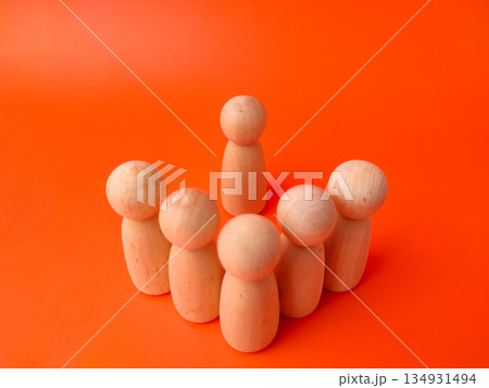 Six wooden peg dolls on an orange background. These types of photos are commonly used as visual metaphors in various contexts, particularly in business, psychology, and education 134931494