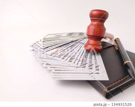 A gavel stack of US currency, a wallet, and a pen on white background. 134931520