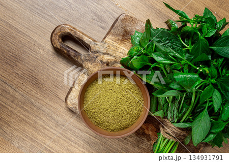 ground green basil, in a ceramic bowl, with a bouquet of fresh green basil, on the table, top view, no people, 134931791