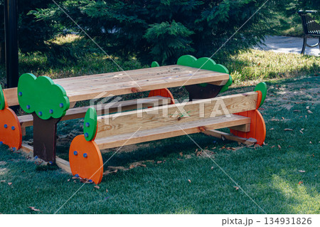 Colorful wooden picnic table in a green park on a sunny day with playful design elements 134931826