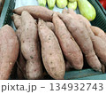 Sweet potatoes on display in a green plastic crate, offering healthy root vegetables for sale in a grocery store, representing fresh produce and organic food choices 134932743