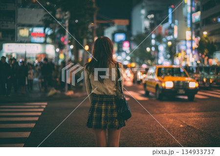 Night Woman Stands at Crosswalk in Busy City Street With Bright Lights and Moving Cars Around Prostitute 134933737