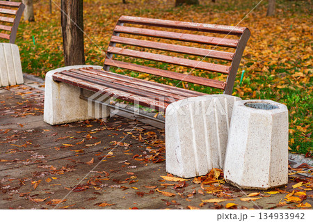 Street bench, paintwork has worn out from atmospheric factors, worn off, exposing wooden benches. Side bearing supports are cast from liquid concrete. Place to relax while walking in park Street bench, paintwork has worn out from atmospheric factors, worn off, exposing wooden benches. Side bearing supports are cast from liquid concrete. Place to relax while walking in park 134933942