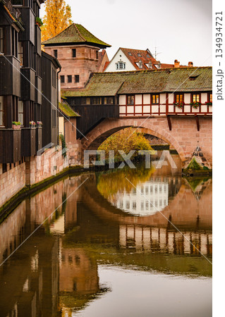 Historic Bridge And Medieval Architecture In Nuremberg: Traditional Half-Timbered Houses Reflected In Calm River Water On An Overcast Autumn Day 134934721