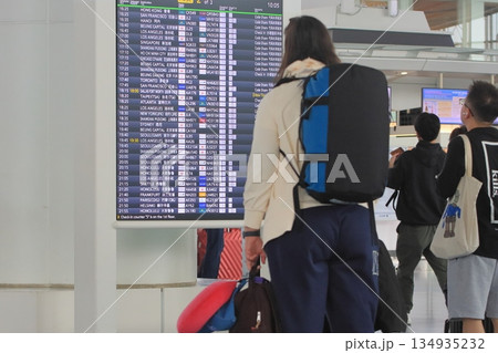 空港の時刻表を確認する旅行客 飛行機の時刻表 空港の時刻表を確認する旅行客 飛行機の時刻表 134935232