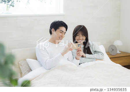 ベッドでスマホを見るカップル 134935635