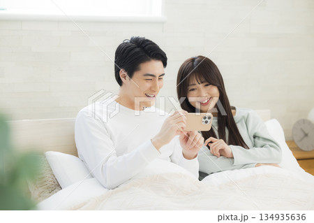 ベッドでスマホを見るカップル ベッドでスマホを見るカップル 134935636