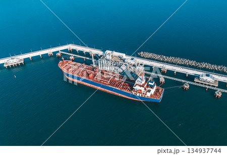 Aerial view of a large oil tanker docked at a pier in the port in process of loading. 134937744