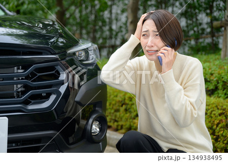 車の前で電話をする女性 134938495